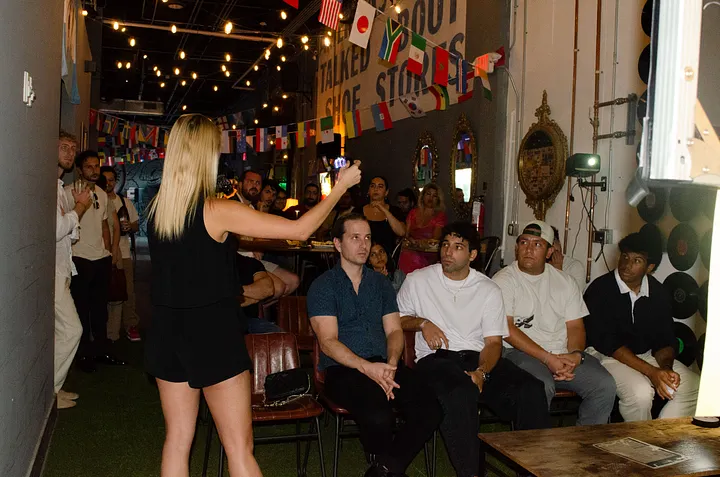 Marla Marquez speaking into a microphone in front of a seated audience at the brewery